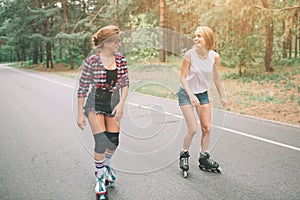 Two slim and young women and roller skates. One female has an inline skates and the other has a quad skates. Girls