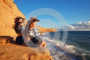 Two slim twins girl in straw hat relax on the beach enjoying life, summer sunset outdoor portrait. People Girlfriend freedom style