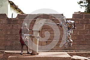 Two Small African Children Joking With A Water Pump