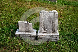 Two small ancient broken gravestones in green grass