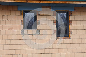 Two small black rectangular windows on the brown brick wall of a building
