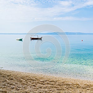 Two small boats in calm water near the sandy shore