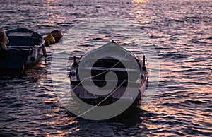 Two small boats floating in the sea at sunset