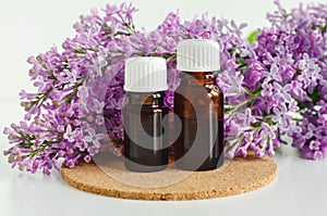 Two small bottles with essential oil tincture, infusion, perfume and lilac flowers. Aromatherapy, spa and herbal medicine
