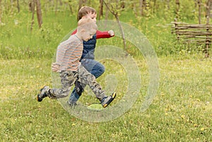 Two small boys running across a field