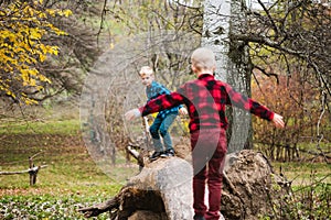 Two small brothers walk on tree trunk