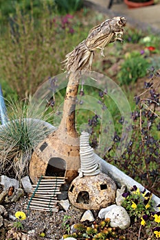 Two small carved out dry squashes made to look like two small fairy houses with wooden stairs entrance