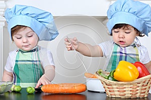 Two small children boy and girl in kitchen apron photo