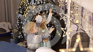 Two small children playing near the Christmas tree