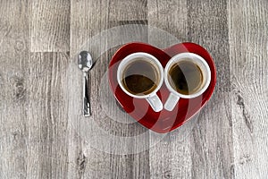 Two small cups of coffee with a heart saucer