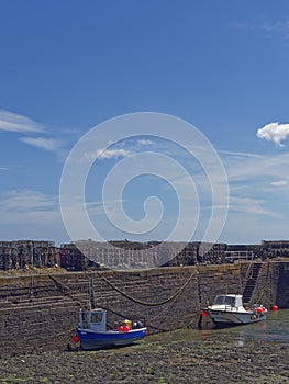 Two Small Fishing Boats alongside the Harbour Walls of Johnshaven Fishing Village at Low Tide