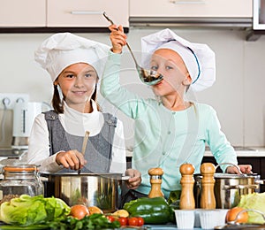 Two small girls cooking vegetable soup