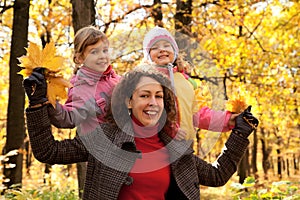 Two small girls with mother in autumnal park