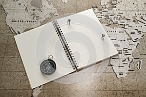 Two small miniatures on white notebook with compass on world map
