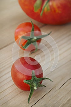 Two small and one large ripe tomatoes on a  table