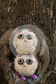 Two small owlets made of wool with beady eyes and a beak made of plastic in light colors