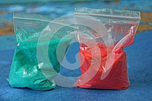 Two small plastic bags with red and green sand