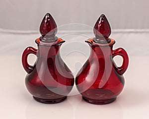 two small red glass jugs with stoppers on white background
