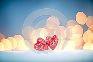 Two small red glitter wooden hearts on a background of bokeh lights. Valentine's day background