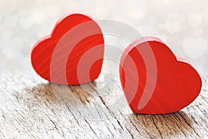 Two small red hearts made of wooden on bright white lights bokeh background. Valentine day background