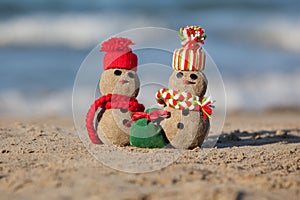 Two small sandy snowmen at tropical beach.