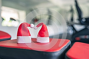 Two small santa hat in the gym opposite the equipment and row of jogging simulators. Symbol and concept of discount offer on Chris