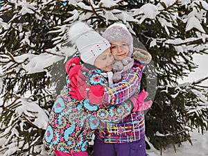 Two small smiling children stand near the Christmas tree. The childhood friendship