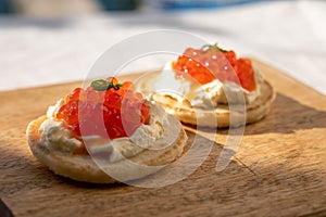 Two small starters blinis with sour cream and salted salmon red caviar served on mango tree wooden board