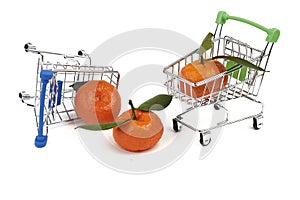 Two small toy cart for groceries from the supermarket and three tangerines with green leaves