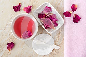 Two small white bowl with rose water (toner), dry rose petals and cotton pad. Homemade cosmetics.