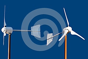 Two Small Wind Turbines Isolated on a Blue Background