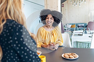 Two smart entrepreneur women talking while taking a break and having a breakfast in the kitchen at coworking place