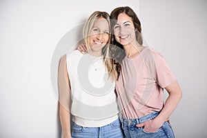 Two smiling best girl friends blond and brunette on white background. Closeup face portrait of two young beautiful women