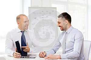 Two smiling businessmen with laptop in office