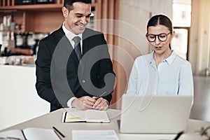 Two smiling businesspeople working on a laptop in an office