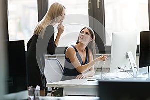 Two smiling businesswomen working with computer together