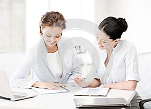 Two smiling businesswomen working in office