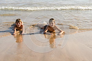 Two smiling children lying on the seashore