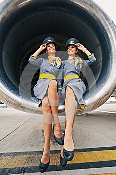 Beautiful stewardesses in uniforms sitting cross-legged inside the turbofan engine photo