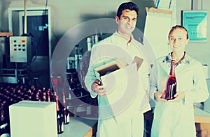 Two smiling employees standing in packaging section on wine manufactory