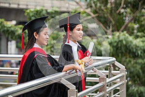 Two smiling female Asian students in graduation gown