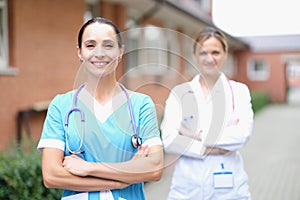 Two smiling female doctors stand with folded arms