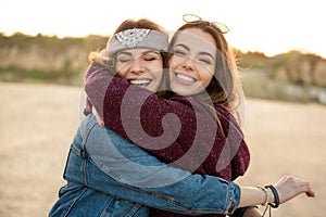 Two smiling female friends hugging each other