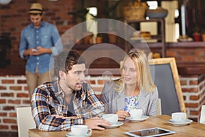 Two smiling friends talking and drinking coffee