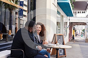 Two smiling friends talking together at a sidewalk cafe