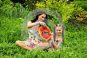 Two smiling girls eats slice of watermelon outdoors on the farm