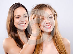 Two smiling girls playing with their beautiful long hairs