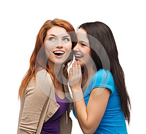 Two smiling girls whispering gossip