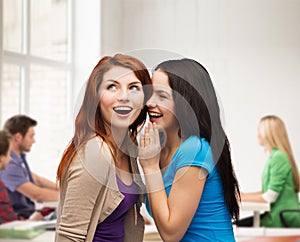Two smiling girls whispering gossip