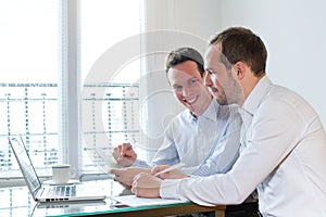 Two smiling happy business men working on project